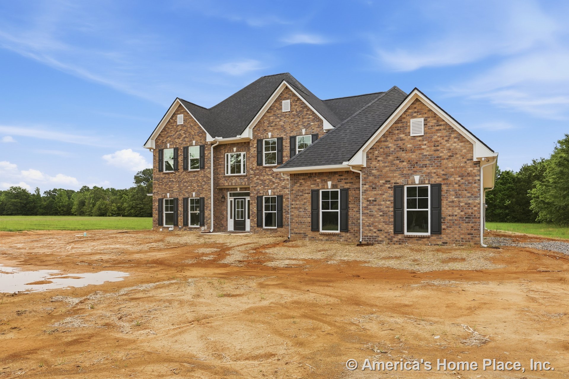 Two-story brick exterior with black shutters, white trim, multiple double-hung windows, gabled asphalt shingle roof, and covered front entry.