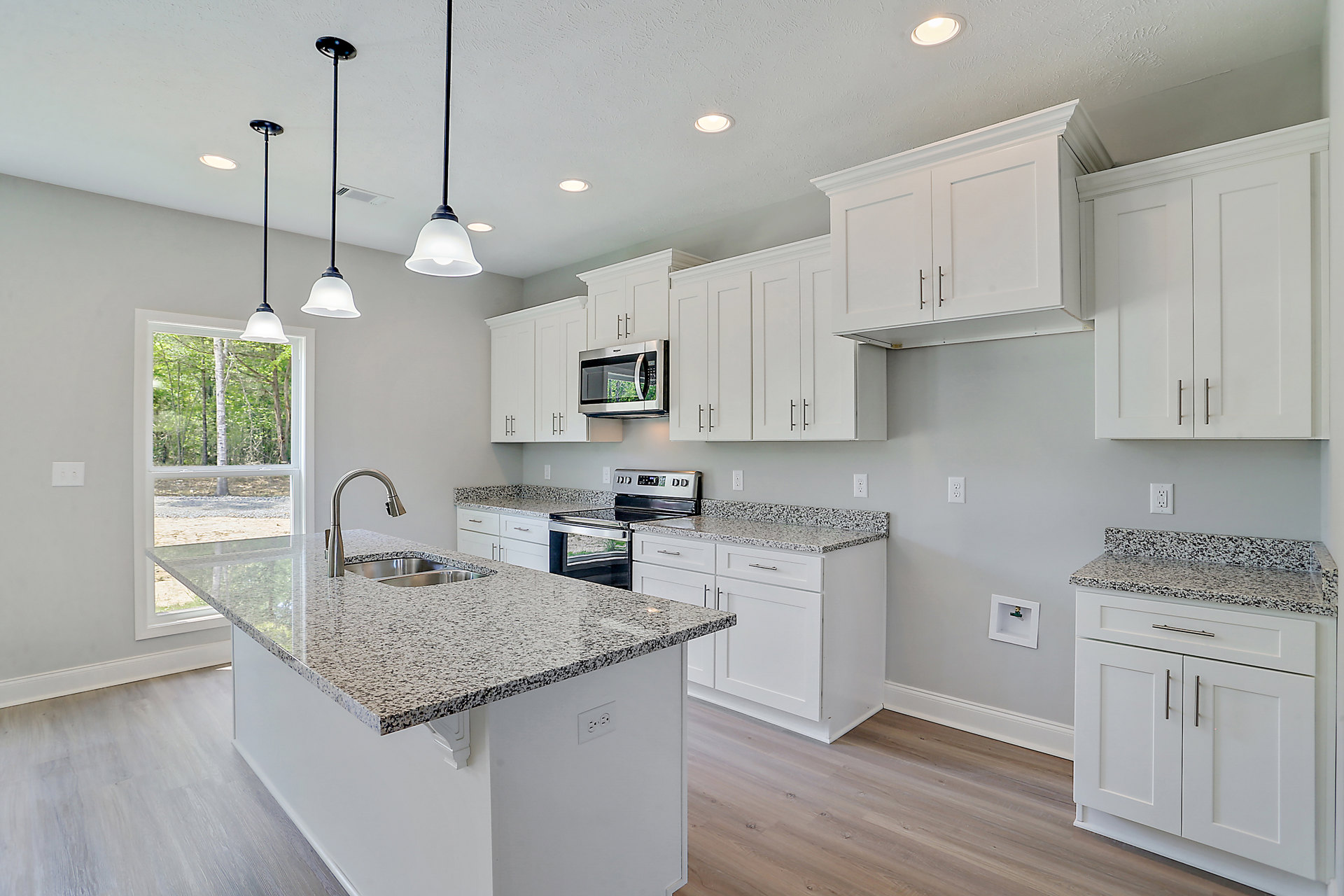Granite countertops and white cabinets in a kitchen with stainless steel stove, built-in microwave, and undermount sink