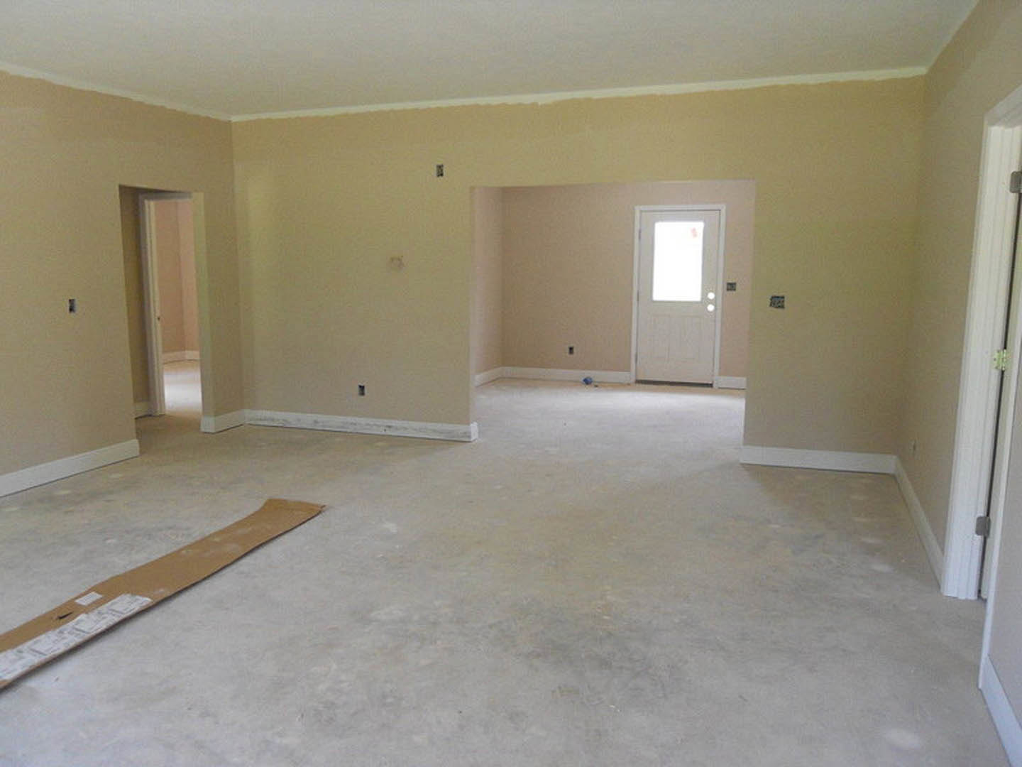 White paneled door with glass window, brown cardboard box on tile floor, plaster walls, close-up of metal door hinge, white rectangular object with red mark near entryway