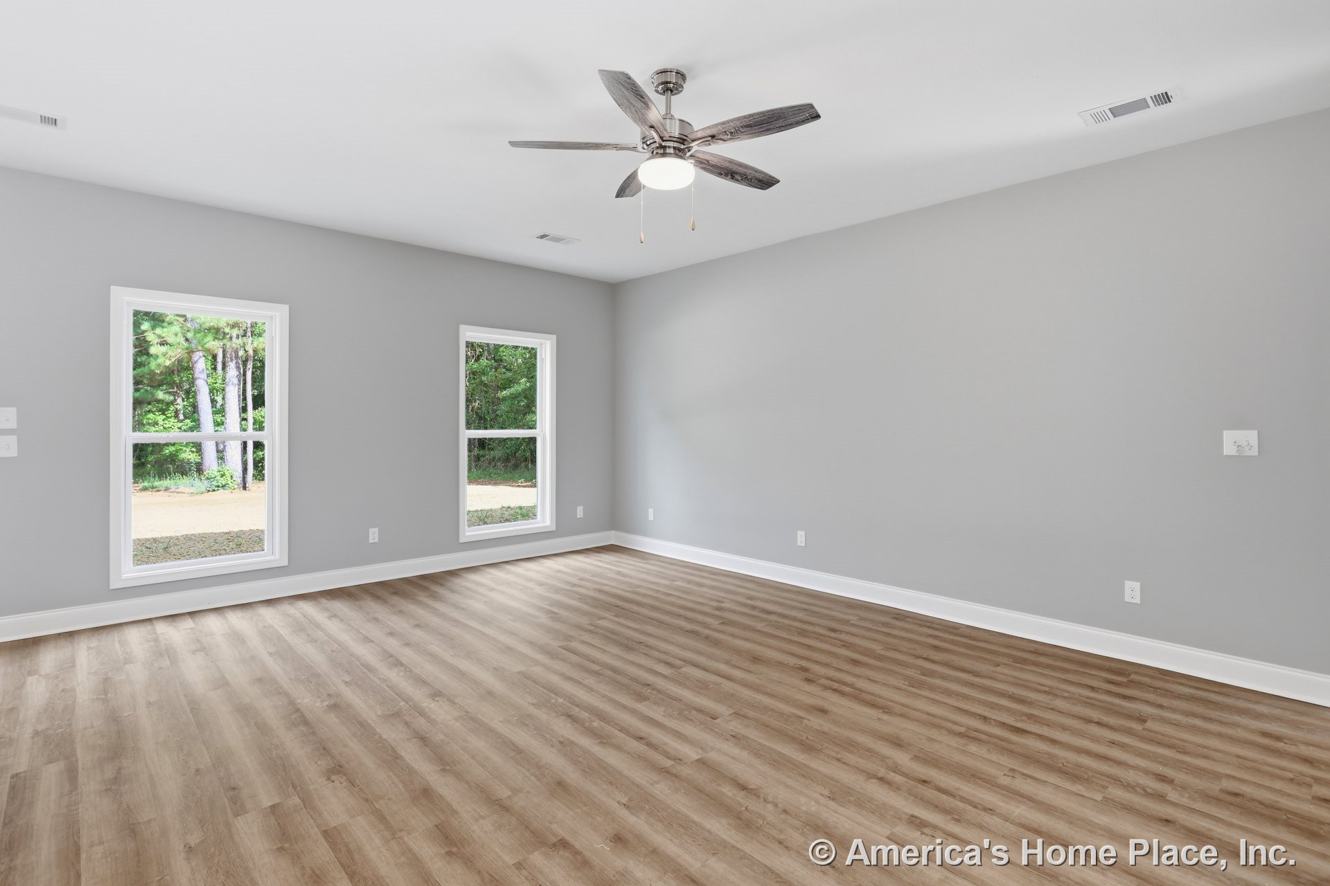 Living room with light wood-look flooring, gray painted walls, white baseboard trim, two large windows, ceiling fan with integrated lighting, smooth white ceiling, and vent covers.