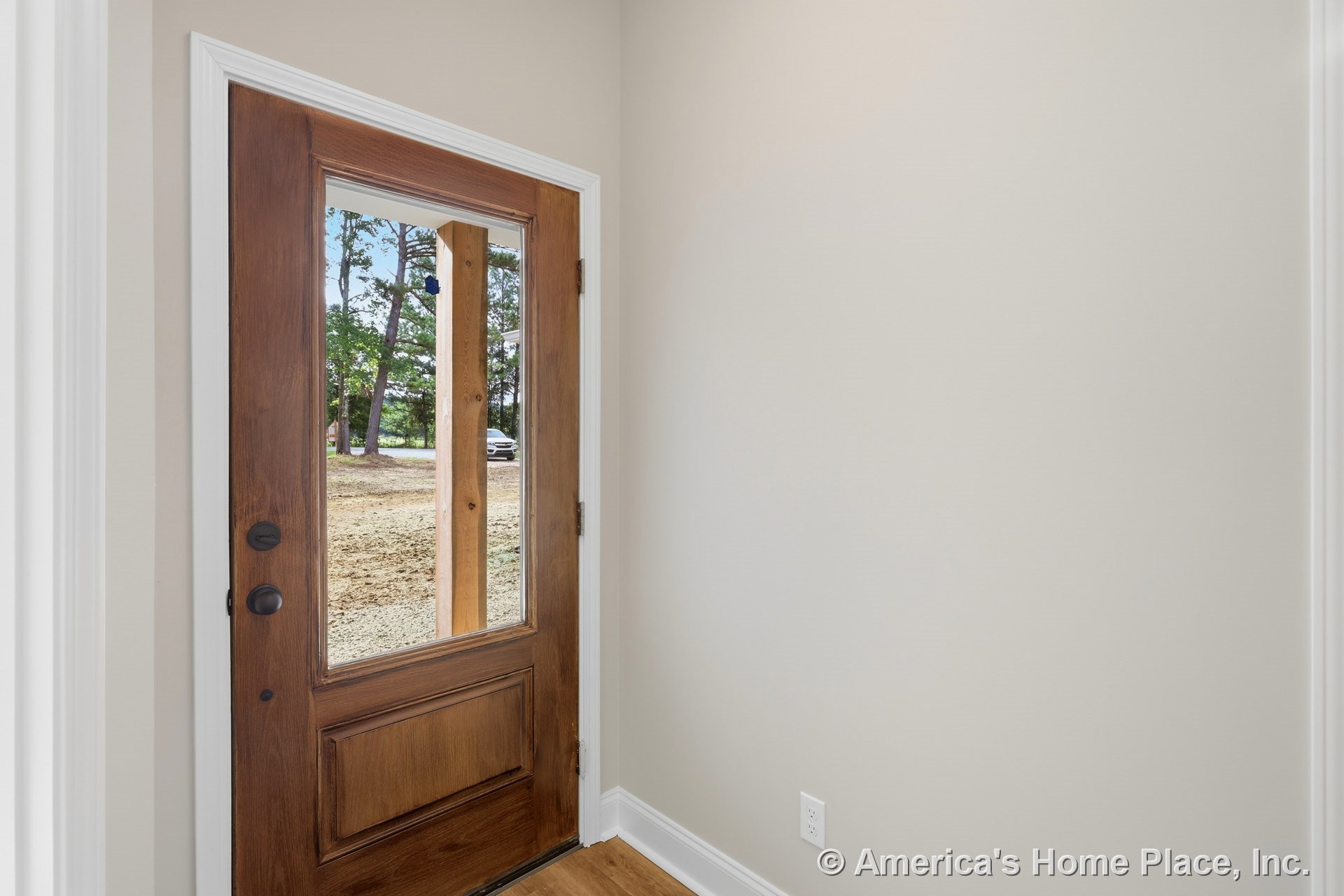 Wooden front door with large glass panel, white trim, light-painted foyer walls, baseboard molding, and hardwood flooring.