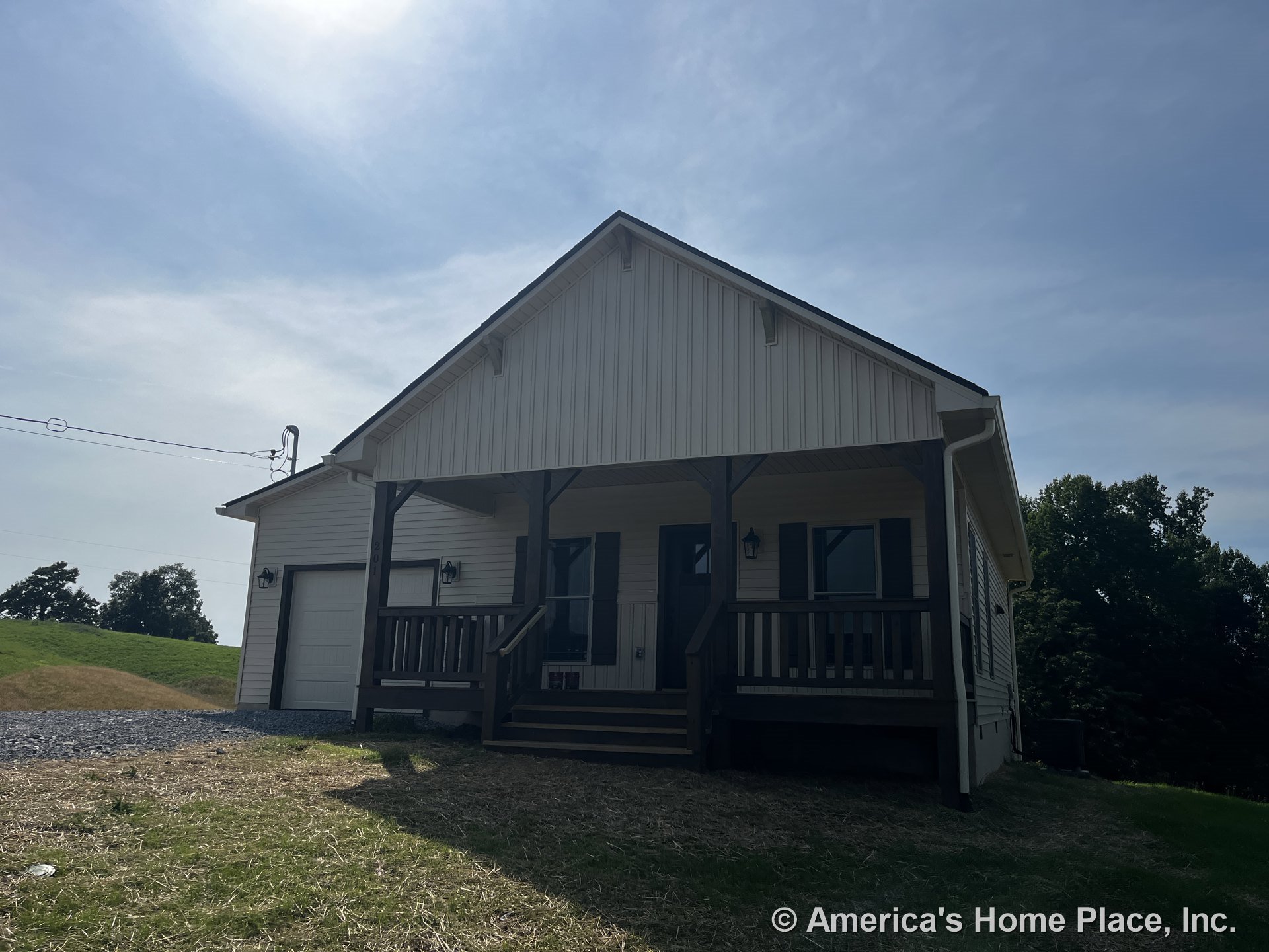 Covered front porch with wood railings and columns, exterior siding, attached garage door, double front windows, exterior lighting fixtures, roof trim, and entry steps.
