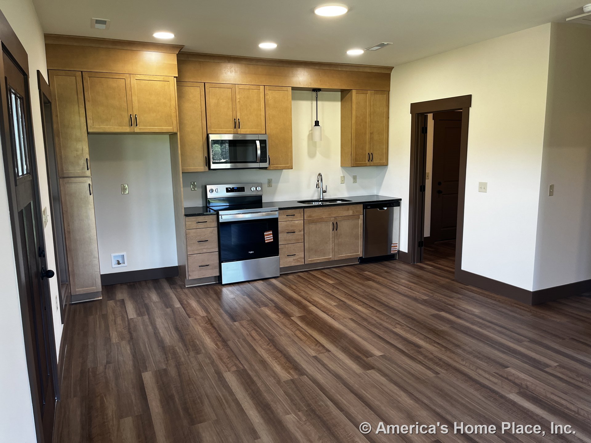 Light wood cabinetry with stainless steel appliances, dark countertops, built-in microwave, electric range, single bowl sink, pendant lighting, recessed ceiling lights, wood-look