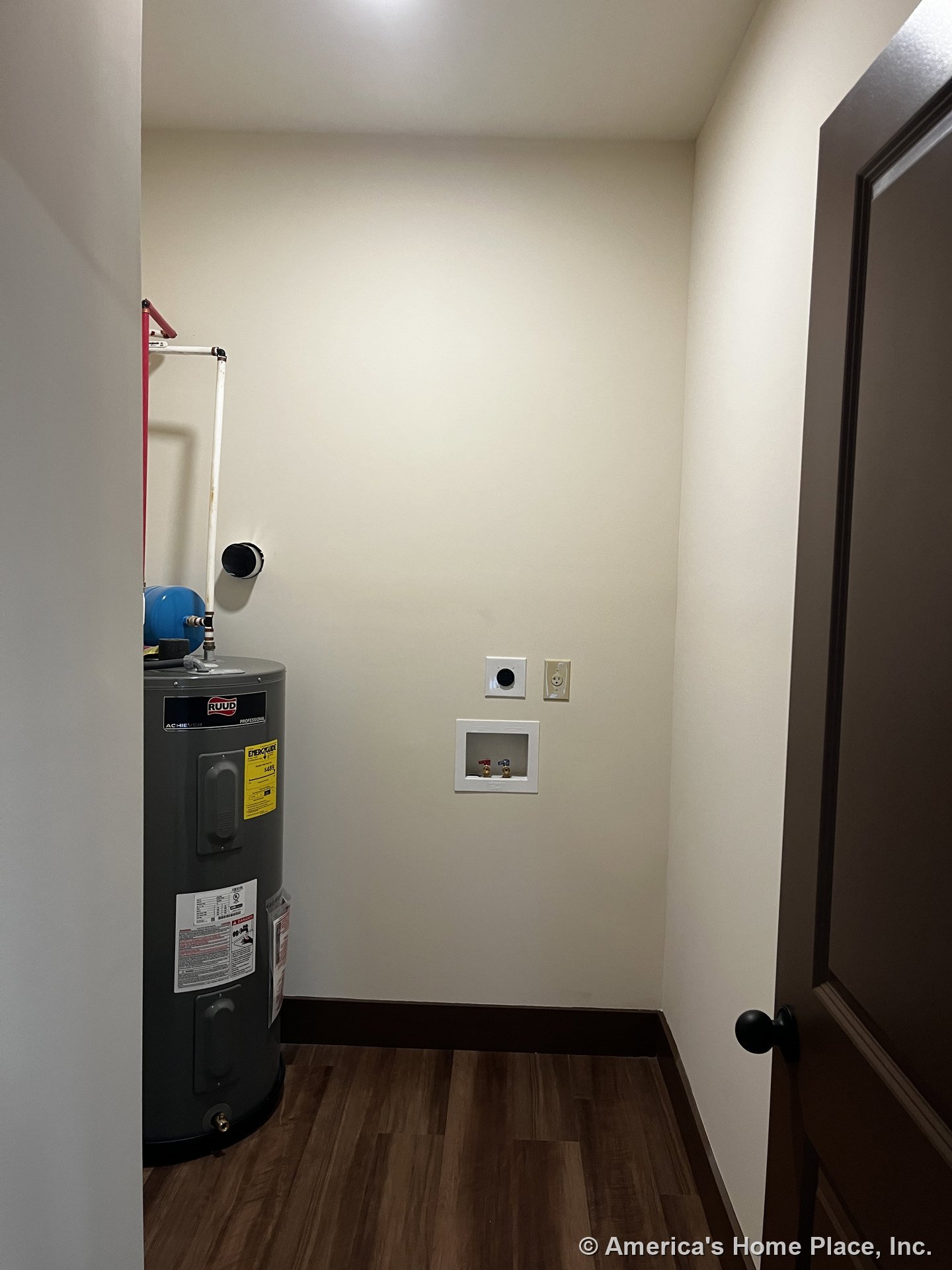 Utility room with water heater, washer and dryer hookups, wood-look flooring, dark trim and door, recessed ceiling light, and neutral wall color