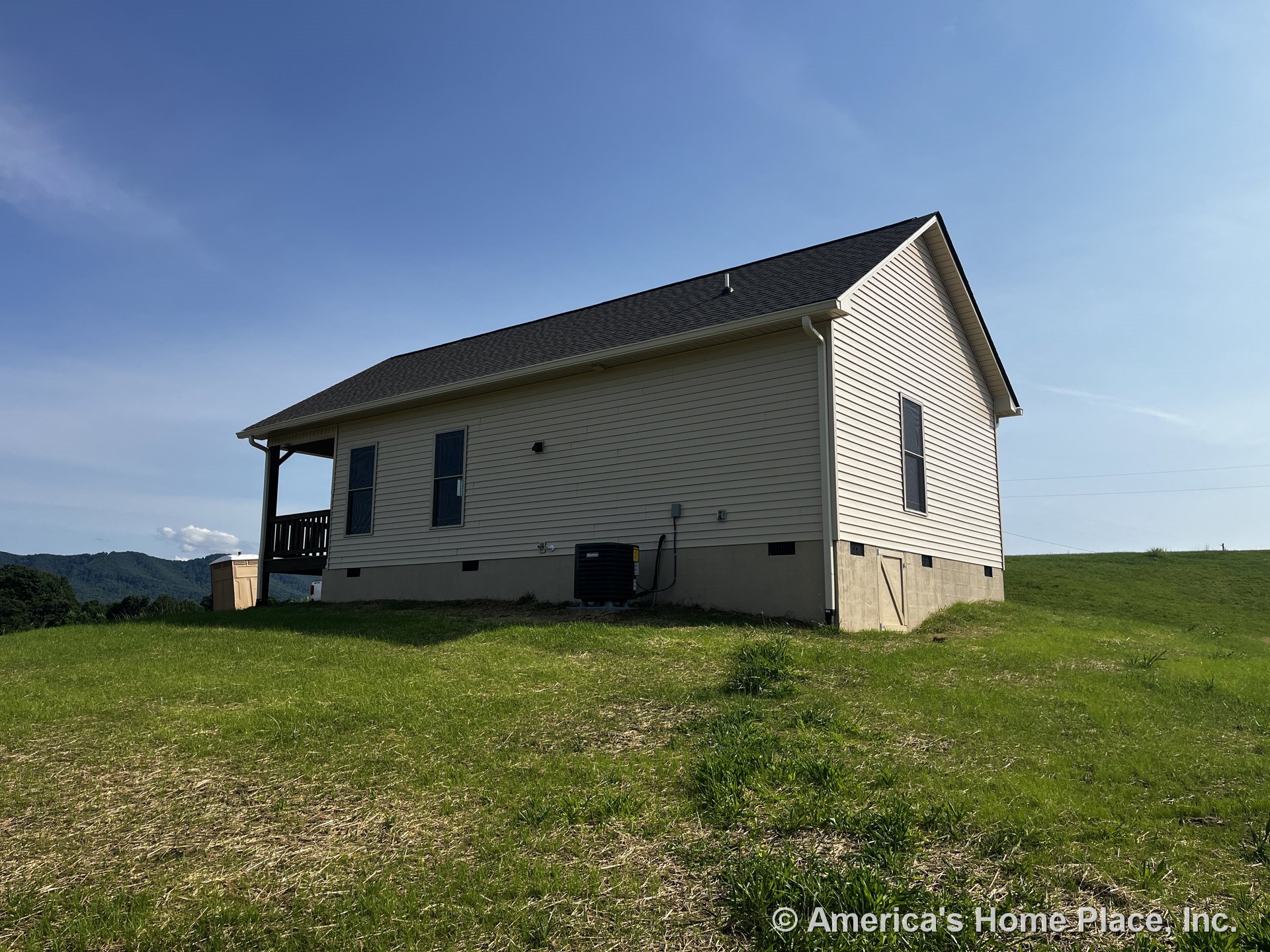 Beige vinyl siding exterior with gable roof clad in asphalt shingles, covered rear porch, concrete foundation, double-hung windows, exterior HVAC unit, utility connections, white
