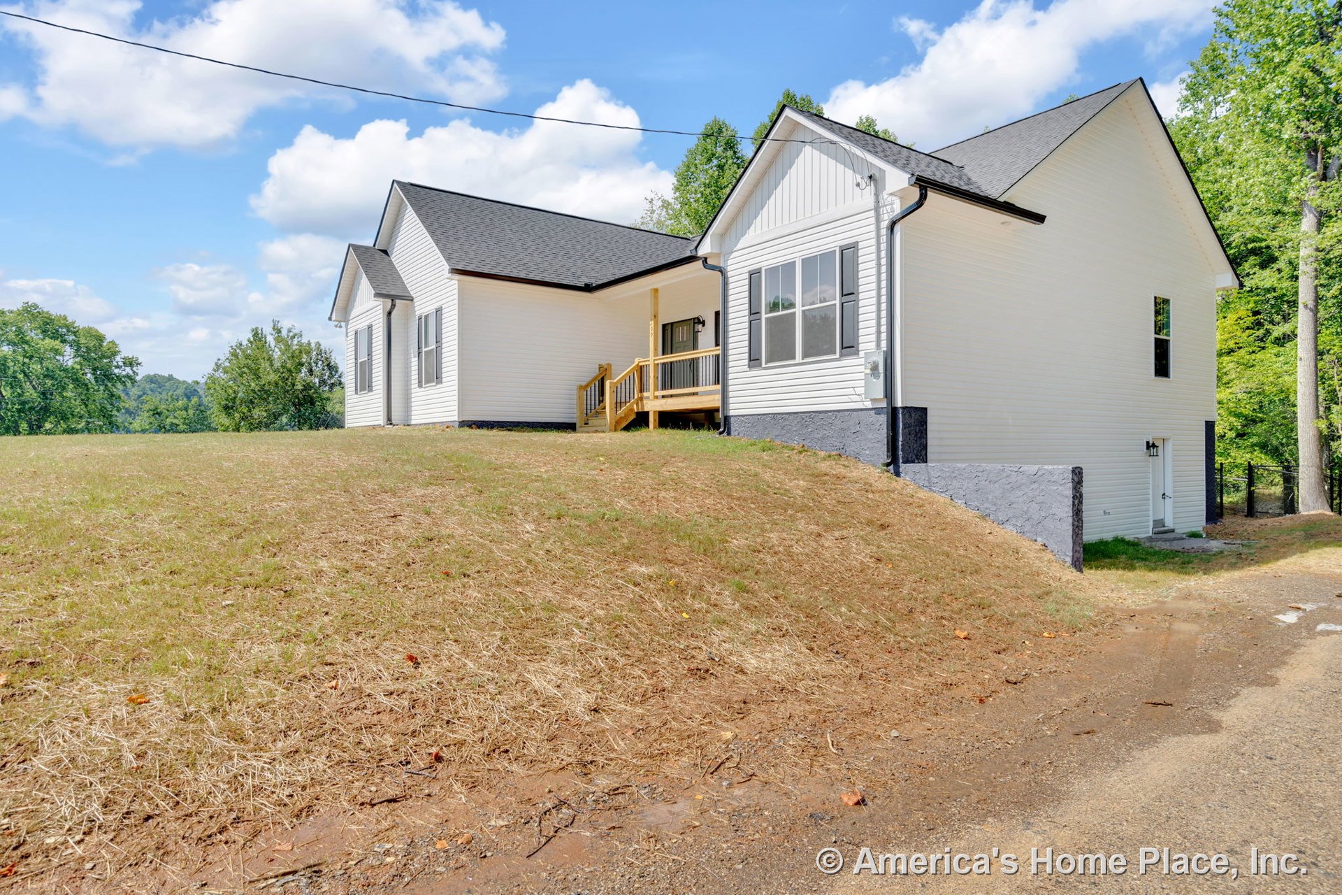 White vinyl siding exterior with black trim and architectural roof, covered front porch featuring wood railings, large windows, concrete foundation, entry door, and outdoor steps.