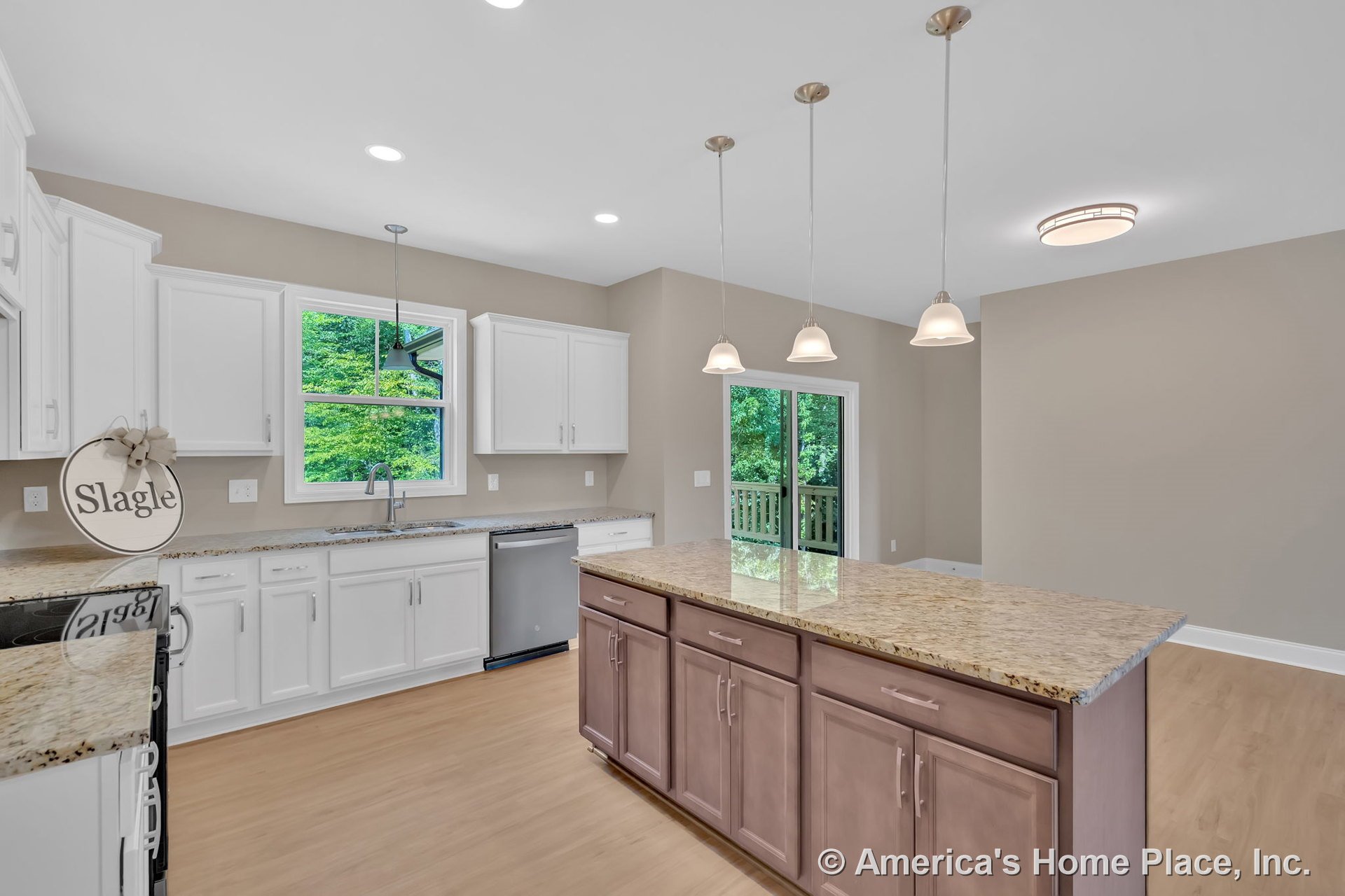 White kitchen cabinetry with granite countertops, central island topped with pendant lights, wood-look flooring, stainless dishwasher beneath window, recessed lighting, sliding