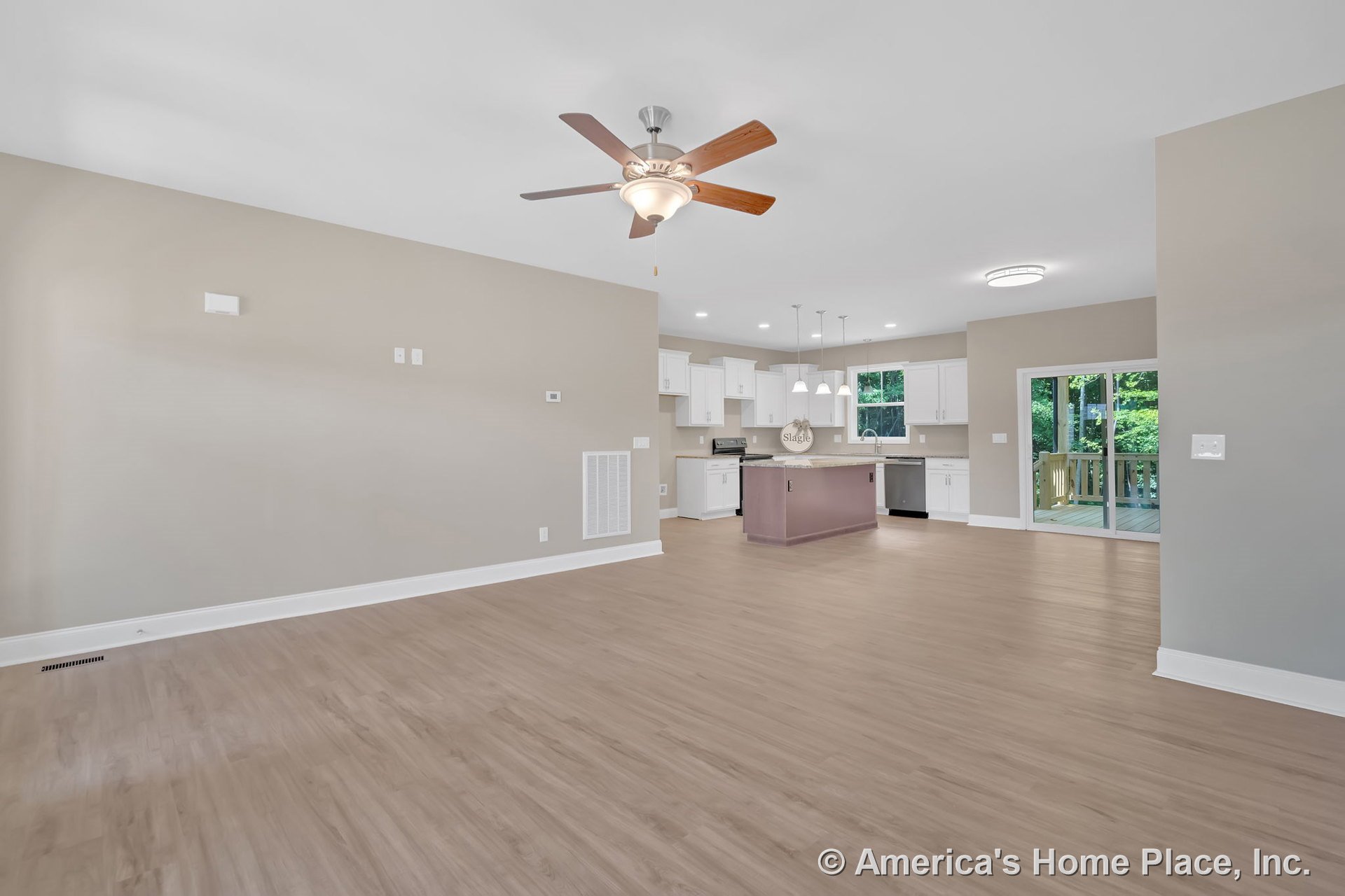 Open-concept living area with light wood flooring, ceiling fan, recessed lighting, and kitchen featuring white cabinetry, central island with pendant lights, stainless appliances