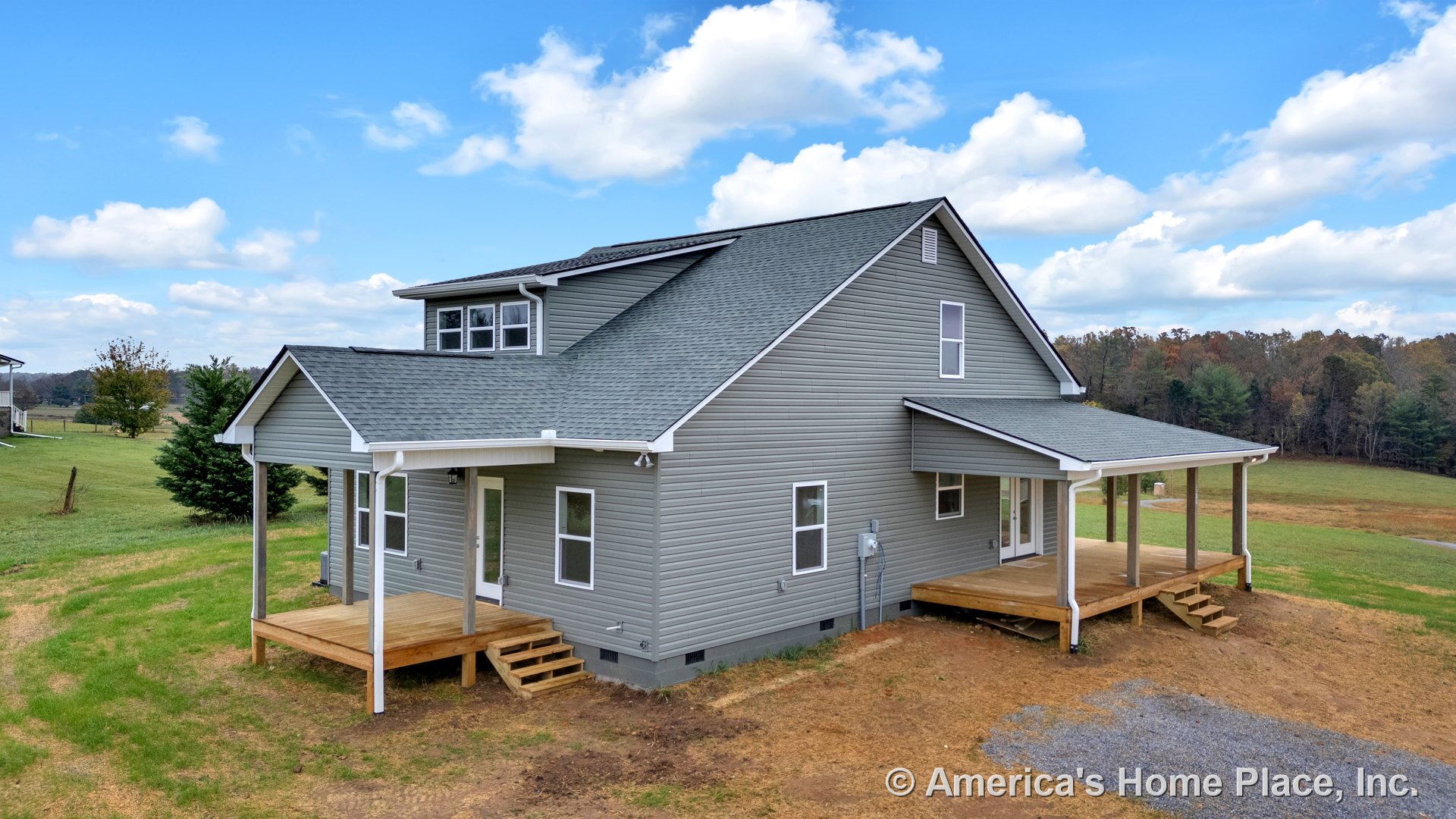 Gray vinyl siding exterior with white trim, gabled asphalt shingle roof, double-hung windows, covered front and side wooden porches with steps, downspouts, and utility meter in a