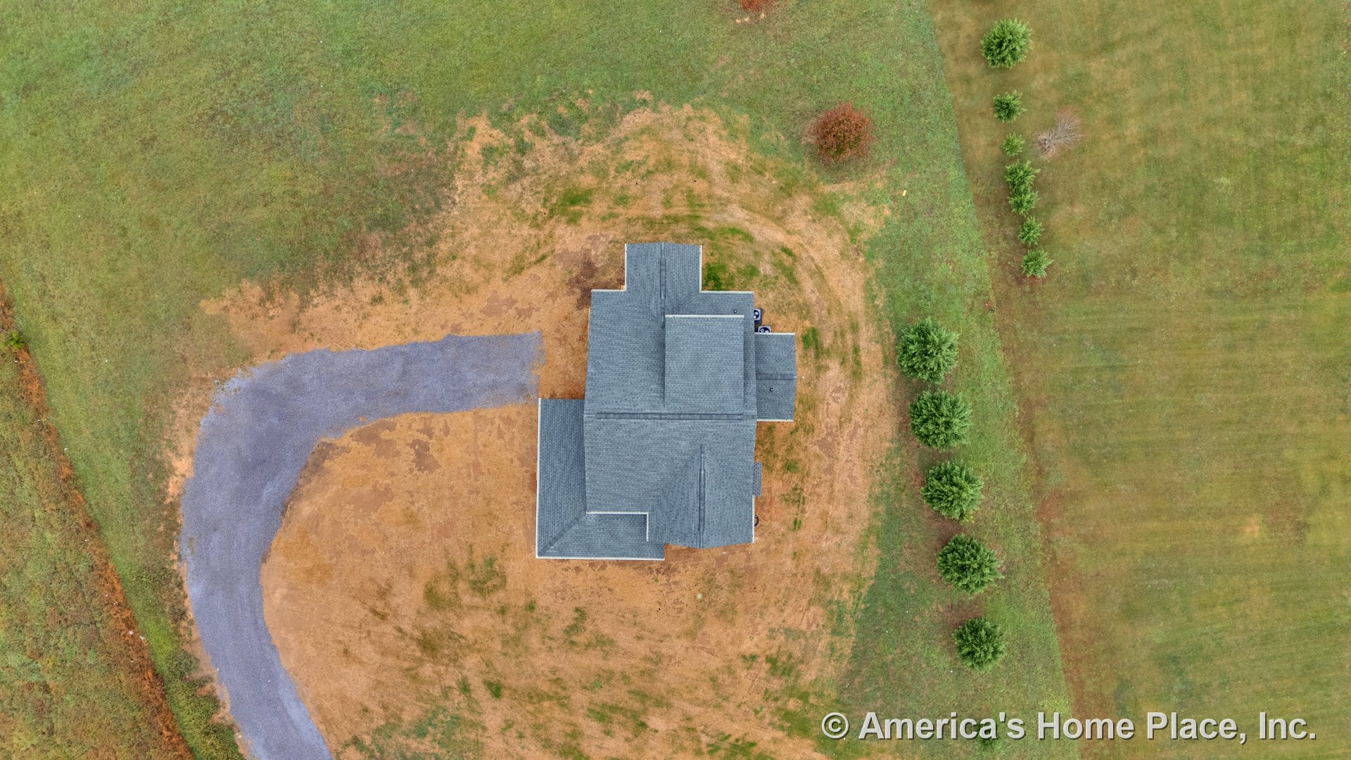 Single-story home with gray shingle roof featuring multiple gables, curved gravel driveway leading to rectangular building footprint, expansive green lawn, and row of small trees