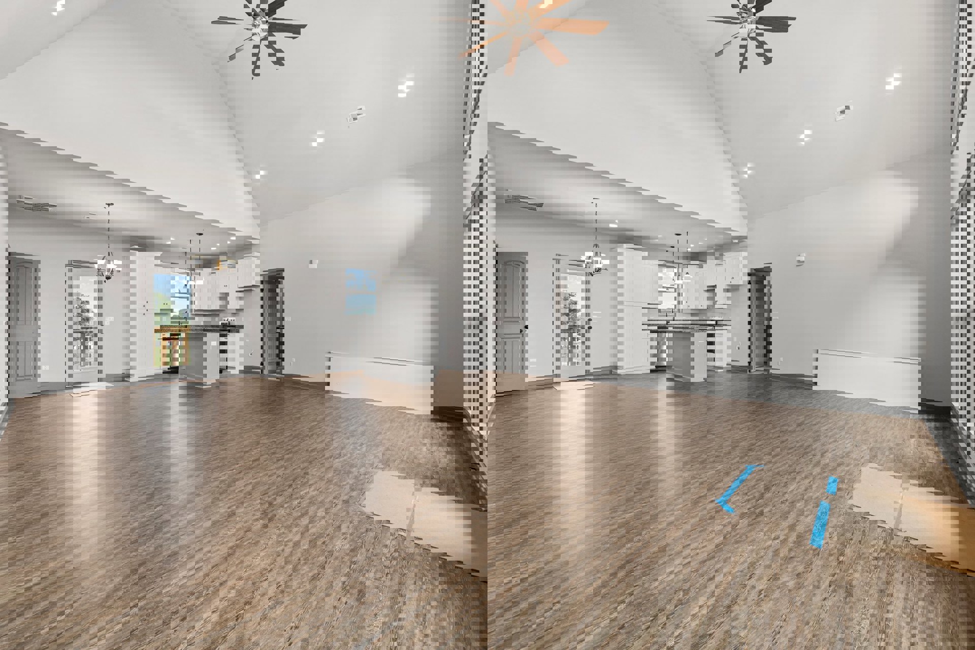 Spacious room with hardwood floor, ceiling fan with light, white door featuring black knob, balcony visible through glass door, cardboard with blue tape on floor