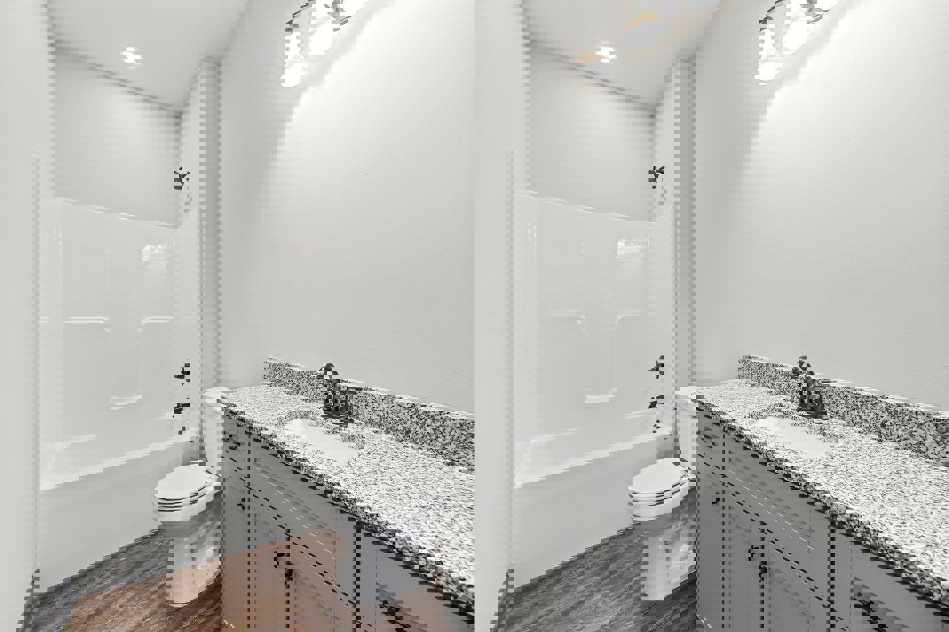 Bathroom with white tile walls, freestanding white bathtub, modern black faucet on sink, white cabinetry, and toilet with closed lid.