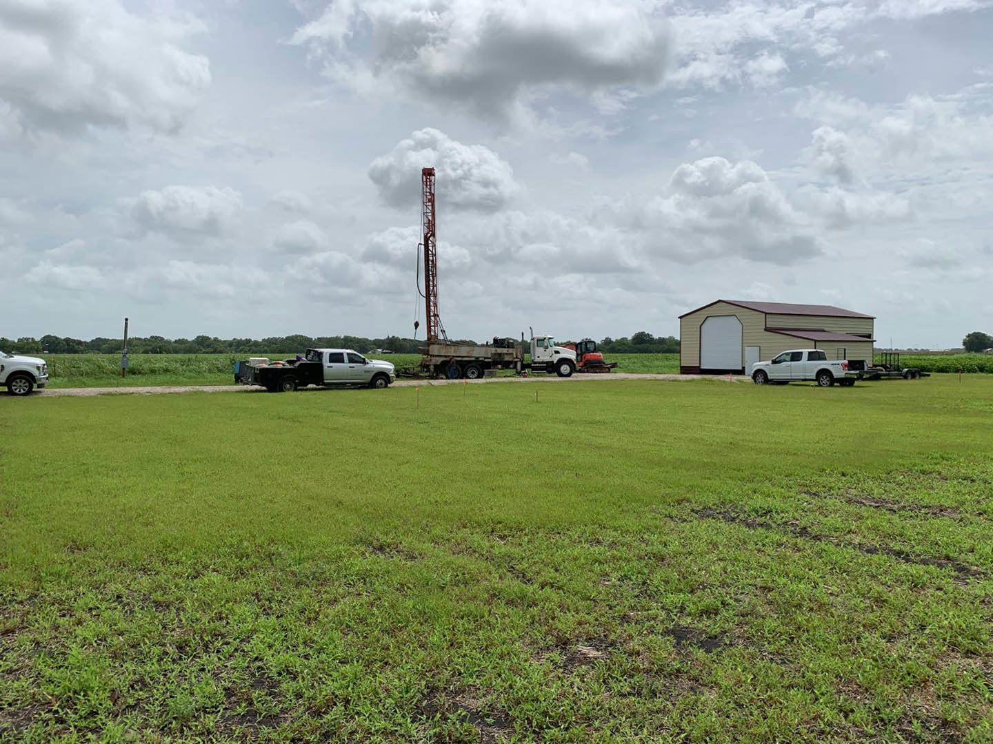 White truck with open doors parked on grassy field under cloudy sky, exterior of custom home visible in background.