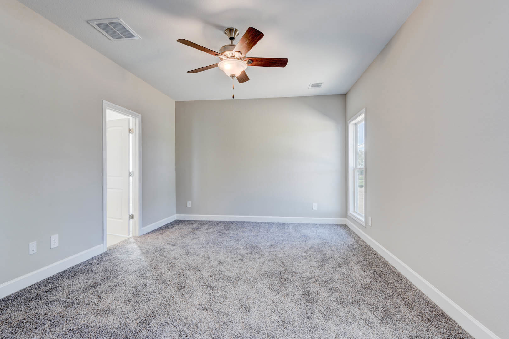 Carpeted room with white walls, ceiling fan with light fixture, wall vent, white door with glass panel, window with white frame