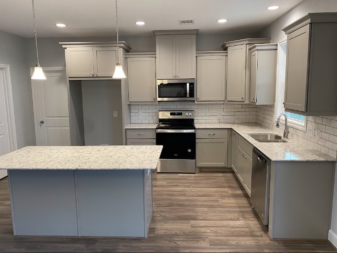 White shaker cabinets, black and stainless steel stove, granite countertops, subway tile backsplash, stainless sink, light tile flooring