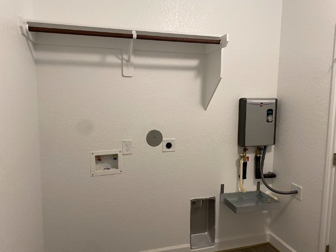 White wall with a metal sink, metal shelf, and a white refrigerator with a dial in a bathroom interior.