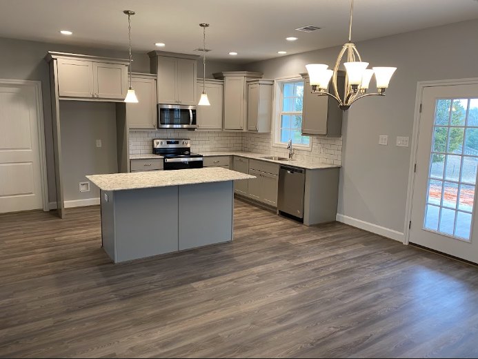Kitchen featuring wood flooring, white cabinetry, stone countertops, stainless steel sink, and recessed lighting on a smooth ceiling