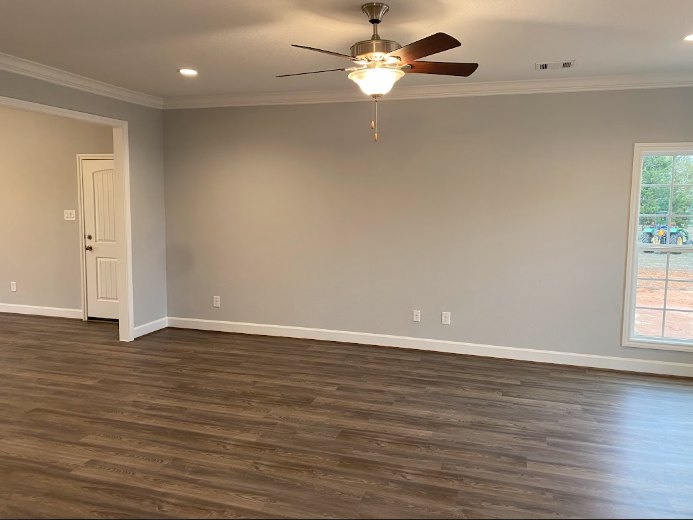 White ceiling fan mounted on smooth plaster ceiling above wood laminate flooring, neutral walls, and minimalist interior decor.