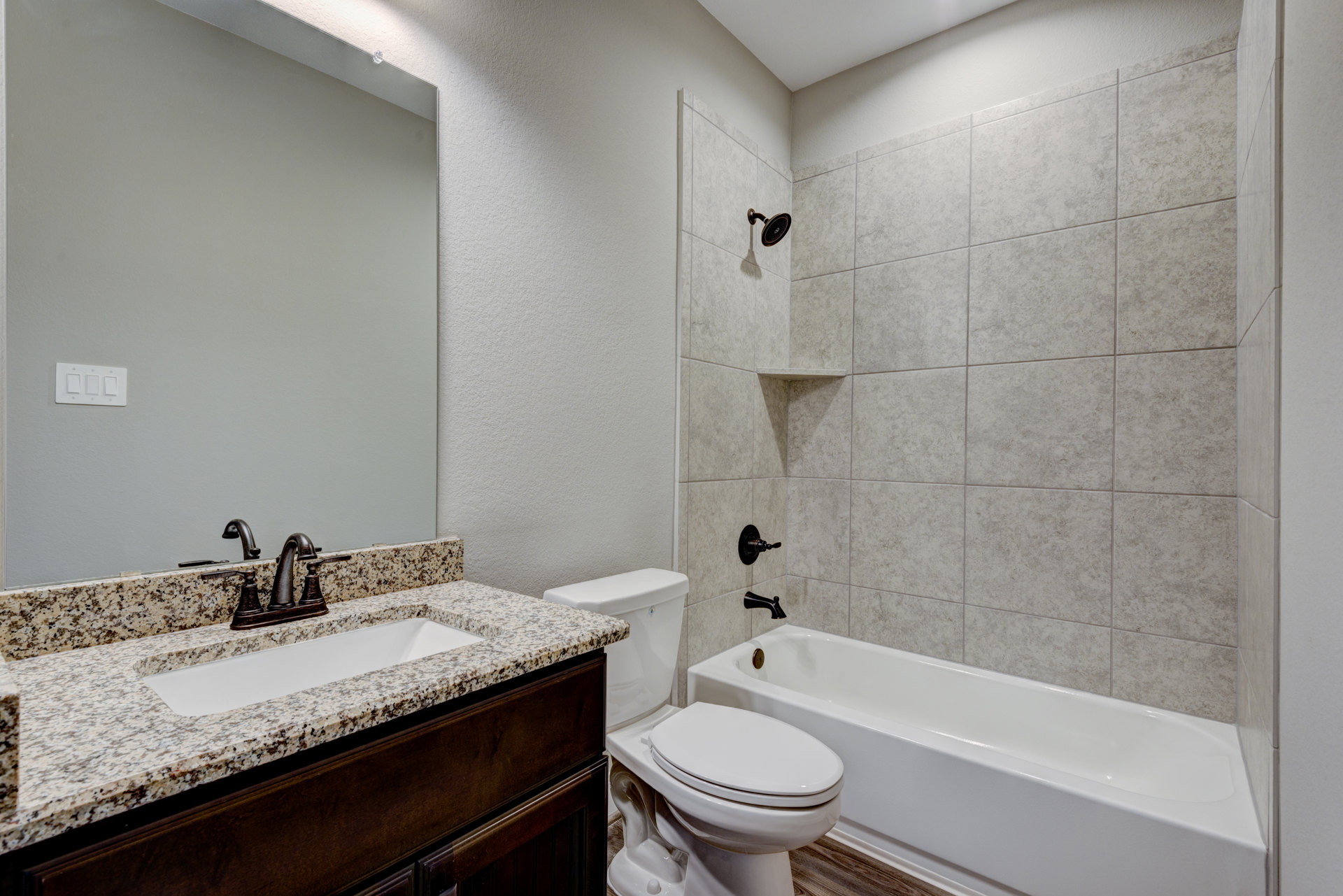 Bathroom with white bathtub beside toilet, marble countertop with sink and faucet, chess pieces arranged on counter, wall-mounted light switch and cabinet knob visible.