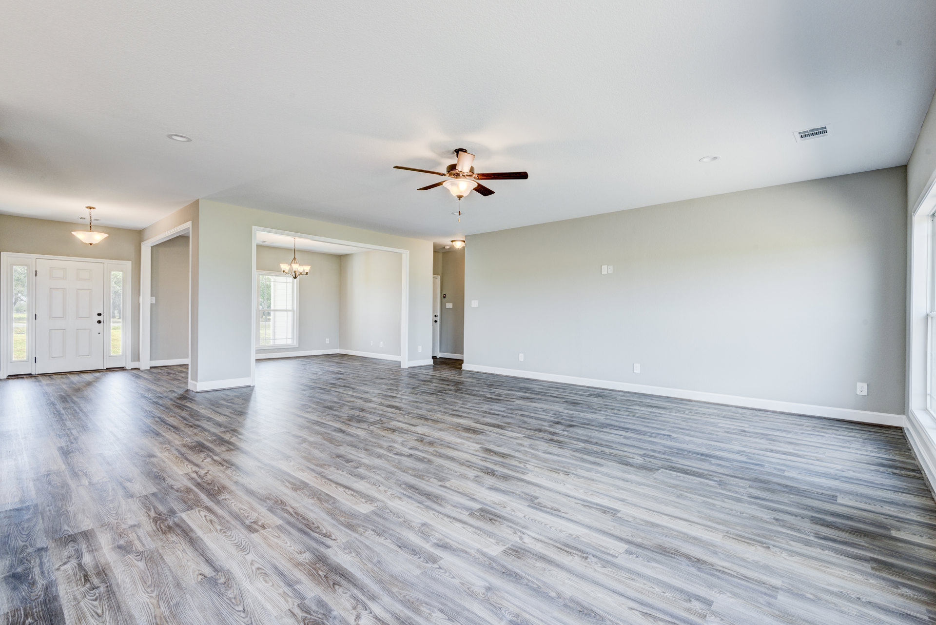 Spacious room with wood flooring, ceiling fan with light, white door featuring glass panes, plaster walls, and smooth ceiling