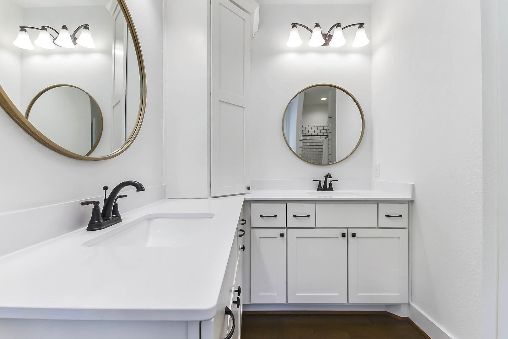 White countertop with black faucet, rectangular mirror above sink, wall-mounted light fixture, partial view of bathroom door and cabinetry