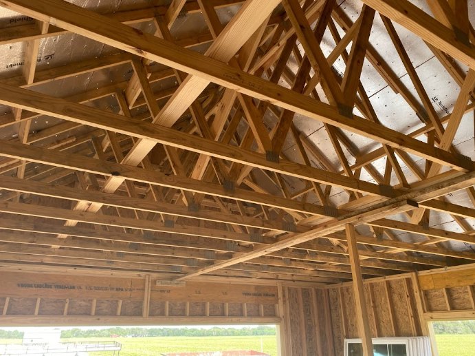 Exposed wooden beams and lumber frame with a metal roof inside a residential building