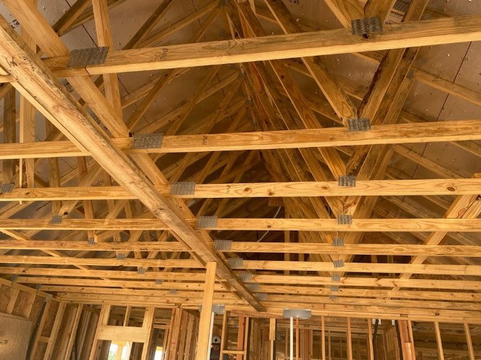 Exposed wooden ceiling beams with natural wood planks and visible insulation in a residential interior