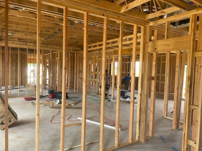 Exposed wood framing and ceiling beams with visible insulation during home construction