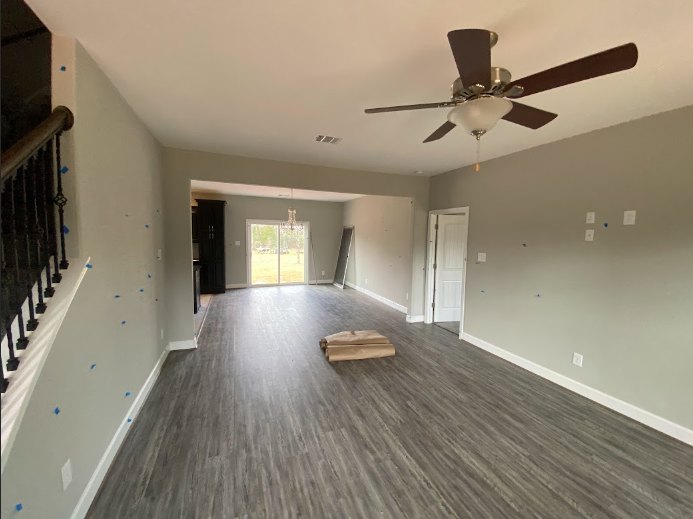 Ceiling fan with light fixture mounted on white plaster ceiling above wood laminate flooring in a residential room with neutral walls.