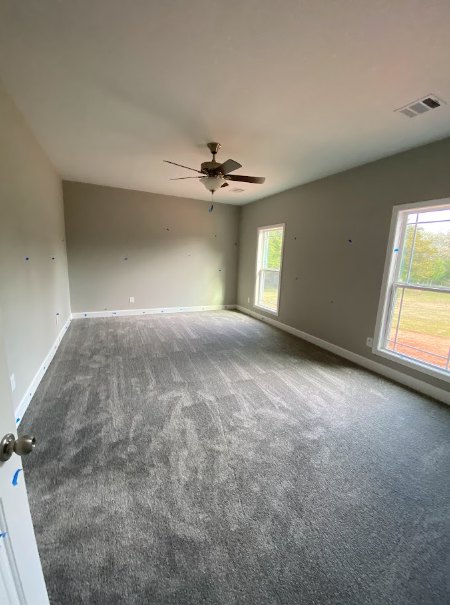 Bright room with plaster walls, wood flooring, large windows, and a ceiling fan with light fixture