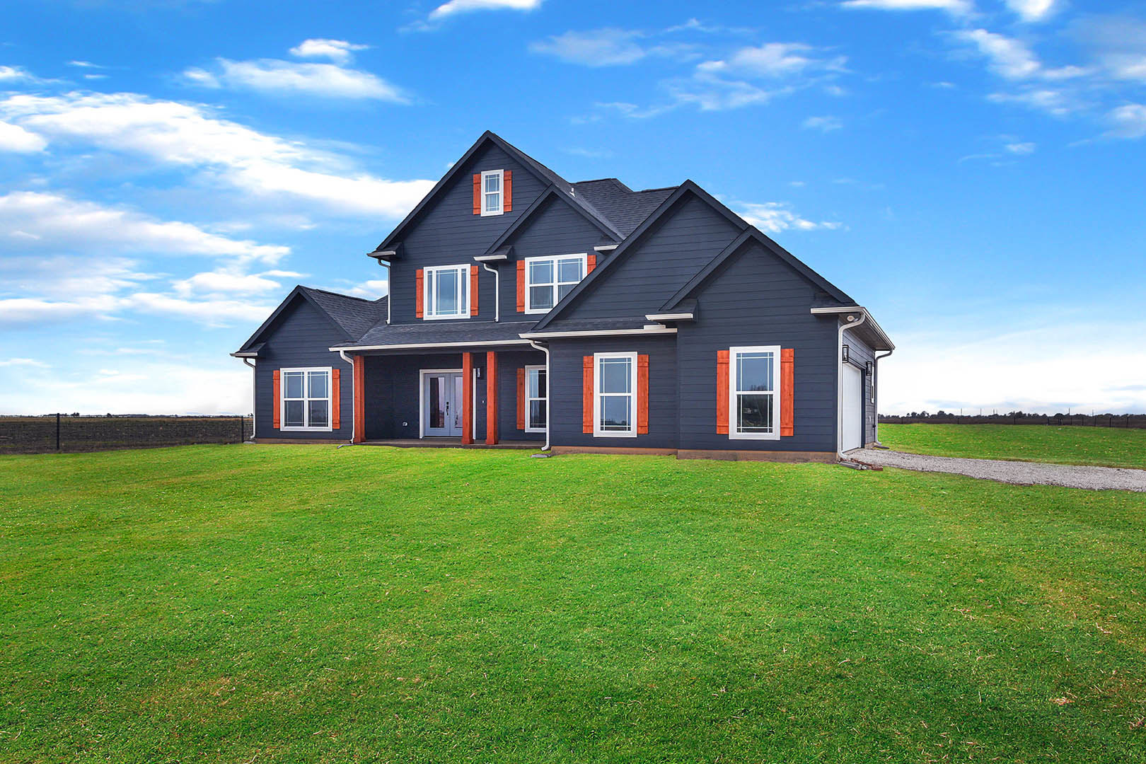 Two-story house with blue roof, white siding, large windows, glass door, and green lawn under partly cloudy sky