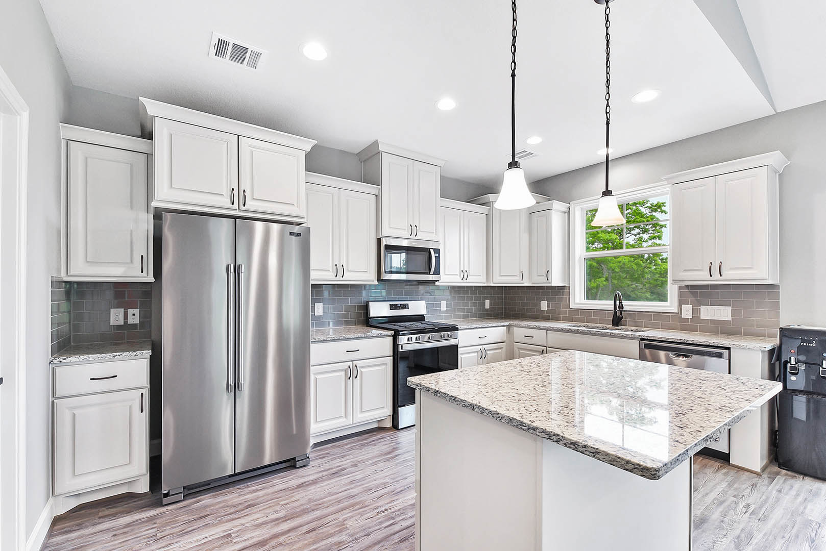 White shaker cabinets, stainless steel refrigerator, built-in microwave, quartz countertops, silver dishwasher, gas stove, white door with glass panel, undermount sink