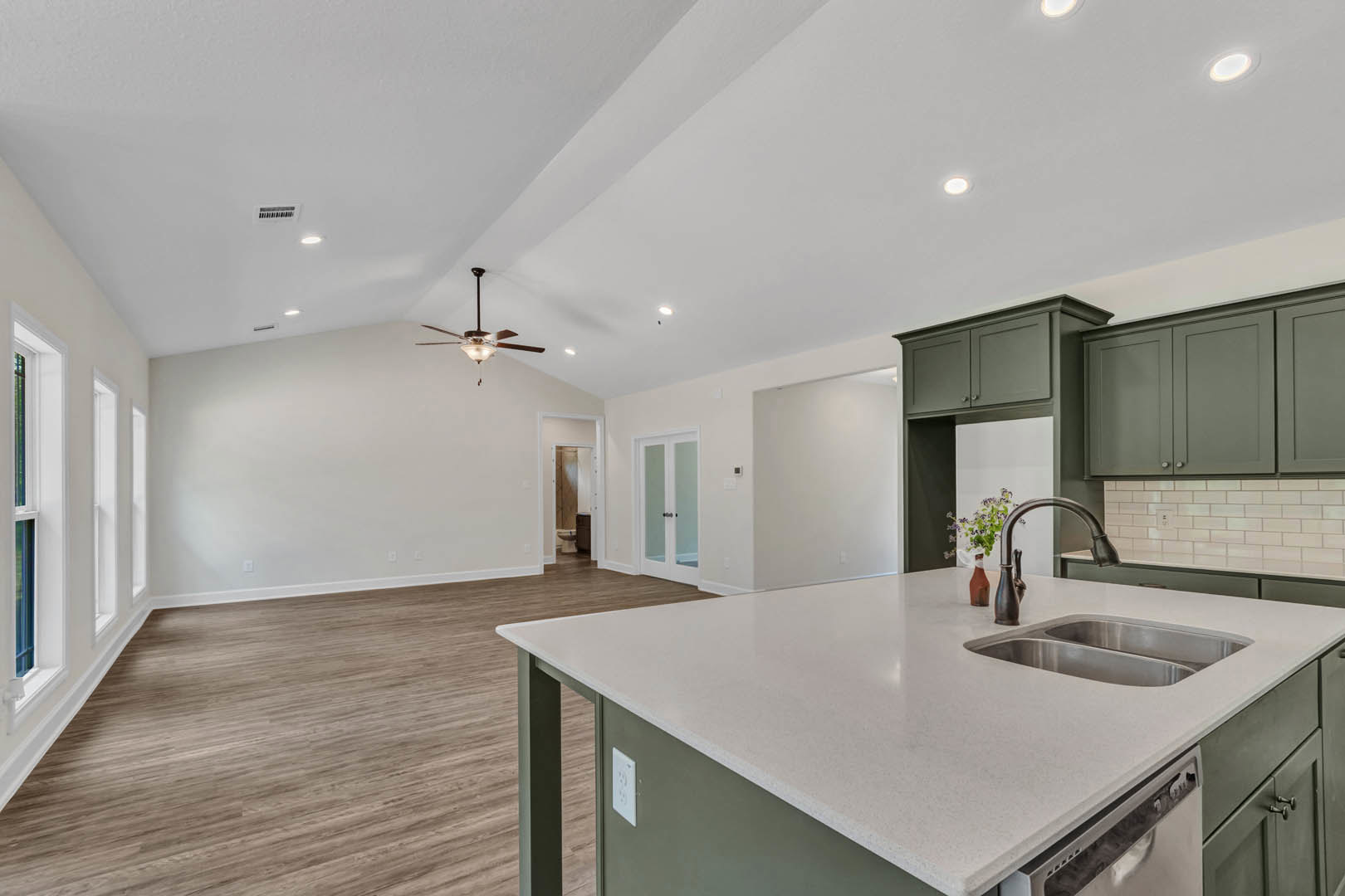 White quartz kitchen island with stainless steel sink, light wood cabinetry, tile flooring, and ceiling fan with light fixture