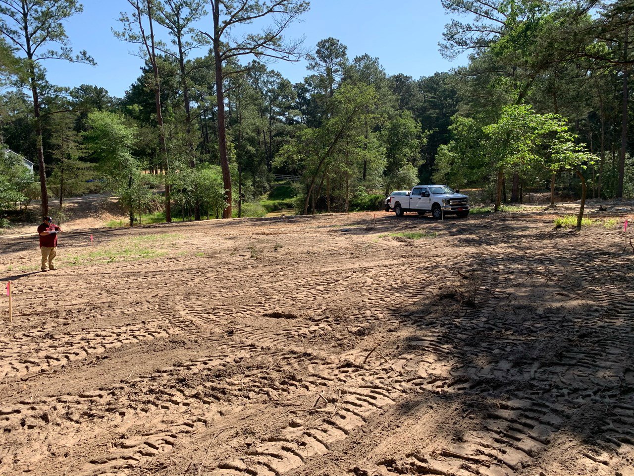 A truck parked in a dirt area with trees in the background.
