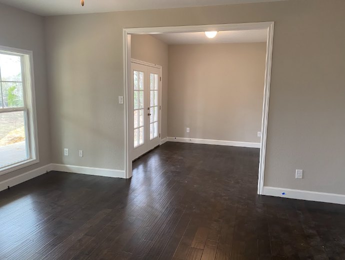 Room with white plaster walls, wood laminate flooring, and a single closed door.