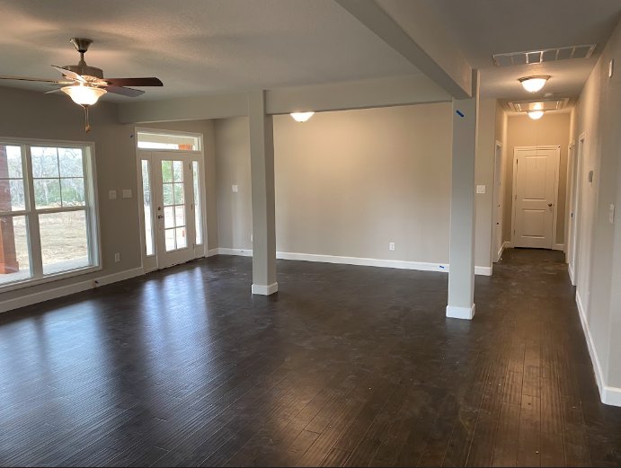 Ceiling fan mounted above wood laminate flooring, white plaster walls, and minimal interior decor in a residential room