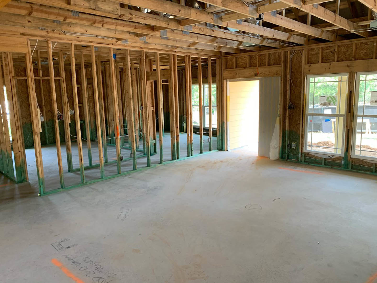 Living room with exposed wood ceiling beams, white-framed window, light-colored walls, and a wooden door