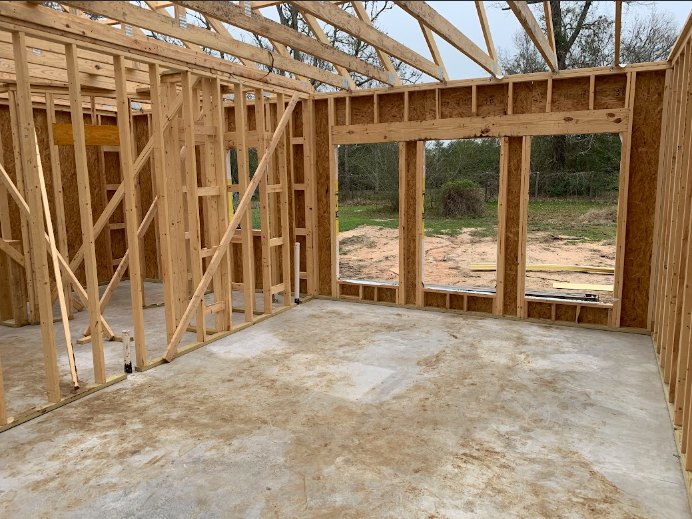 Wooden house frame with exposed beams and planks on a dirt construction site