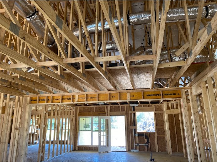 Exposed wood framing and ceiling beams with visible silver HVAC ducts and building insulation
