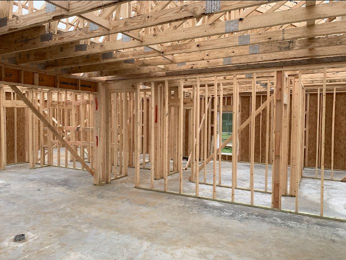 Exposed wood framing and beams with construction materials and insulation in a partially built residential interior