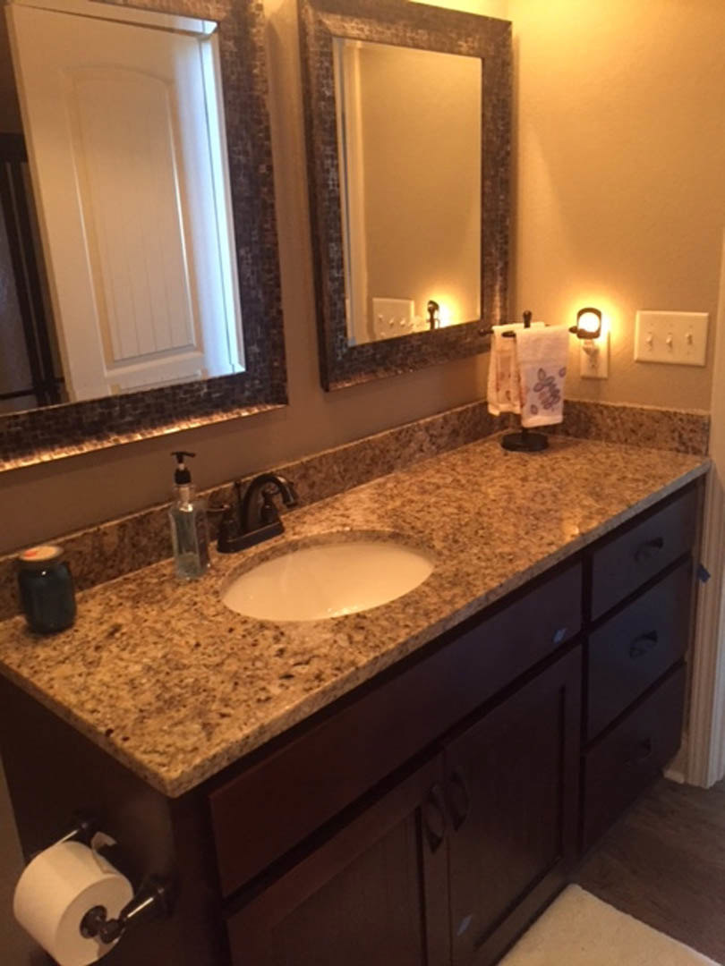Bathroom with marble countertop, dual rectangular mirrors above sinks, white cabinetry, chrome faucets, soap dispenser, and wall-mounted light switches