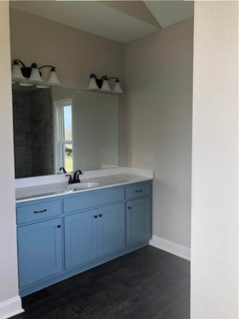 Bathroom with blue ceramic sink, rectangular mirror above, white tile walls, modern faucet, and white pendant lamps.