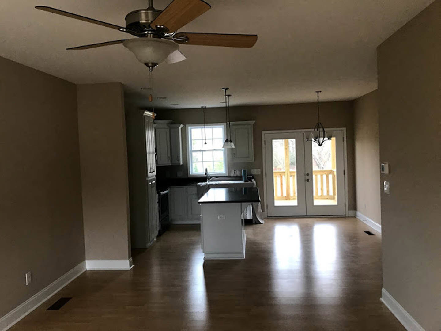 Open kitchen and dining area featuring a ceiling fan with light, white rectangular dining table with black top, double glass-paneled doors, window with natural light, and close-up