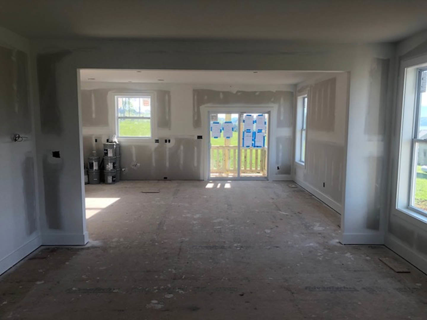 White-walled room with light wood flooring, a window overlooking grass, and a door with signs attached