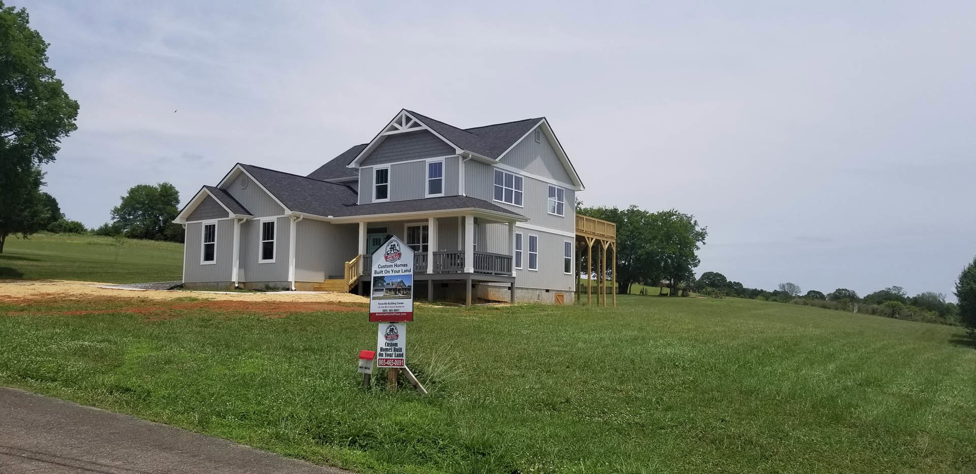 White cottage-style home with gabled roof, surrounded by green lawn and mature tree, wooden post sign labeled "Olson House" positioned in front yard.