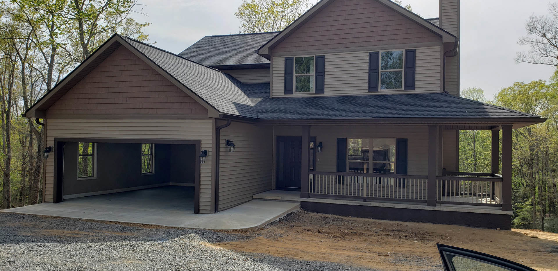 Two-story home with white siding, attached garage, concrete driveway, black front door, white-framed windows, blue shutters, and porch with white railing