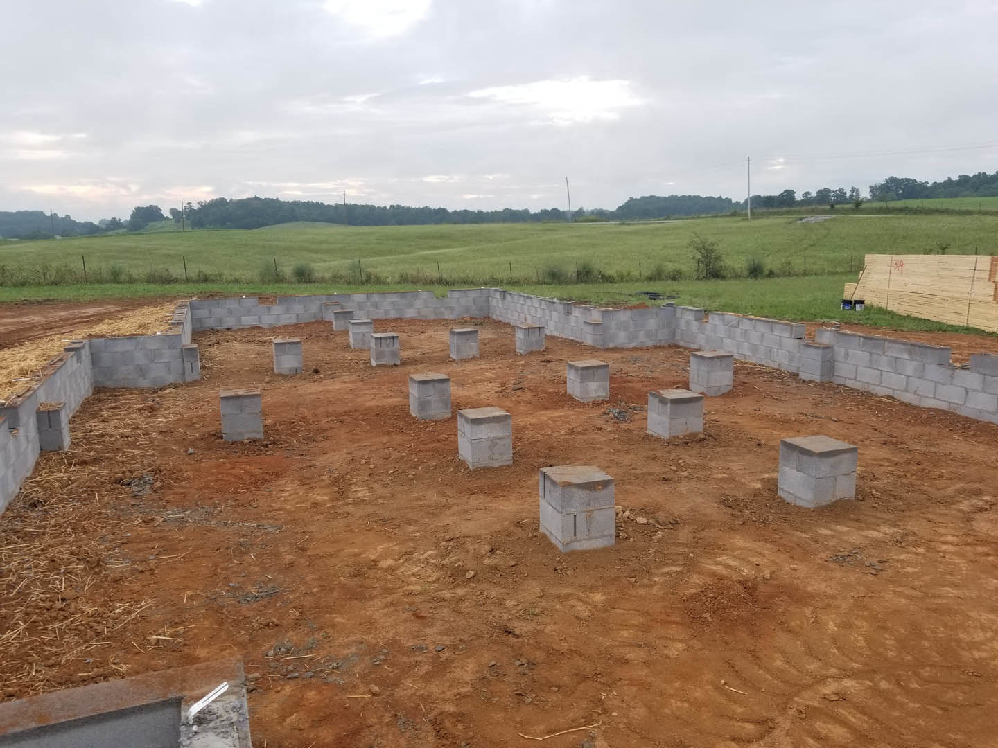 Concrete blocks stacked on a dirt construction site with grass and cloudy sky in the background
