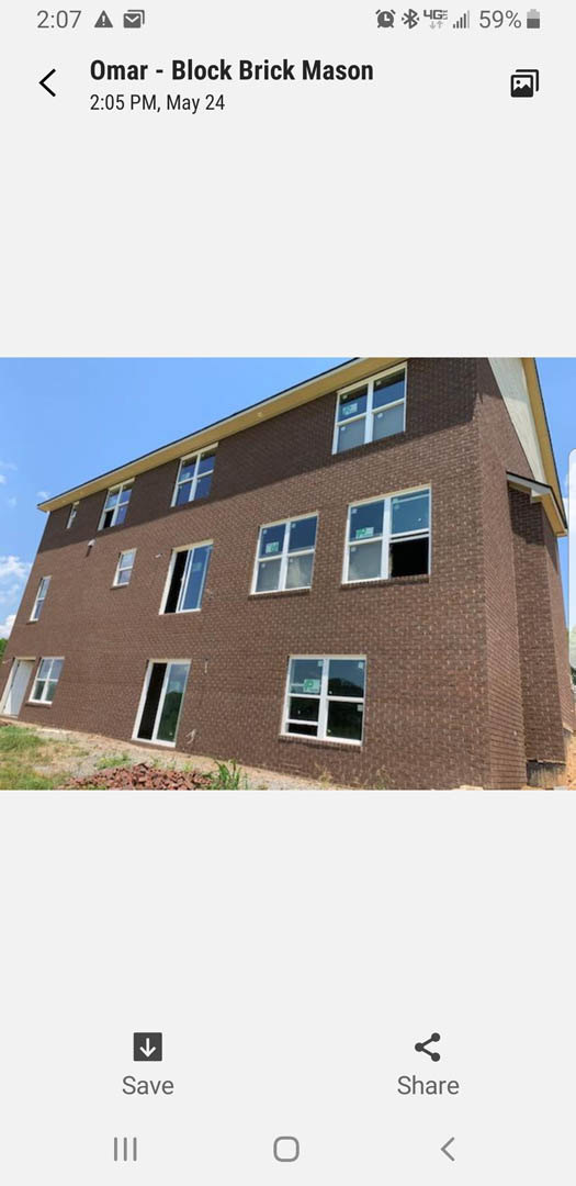 Red brick exterior with multiple rectangular windows, one window featuring an open door and another displaying a sign; broken glass visible on a window, blue sky in background
