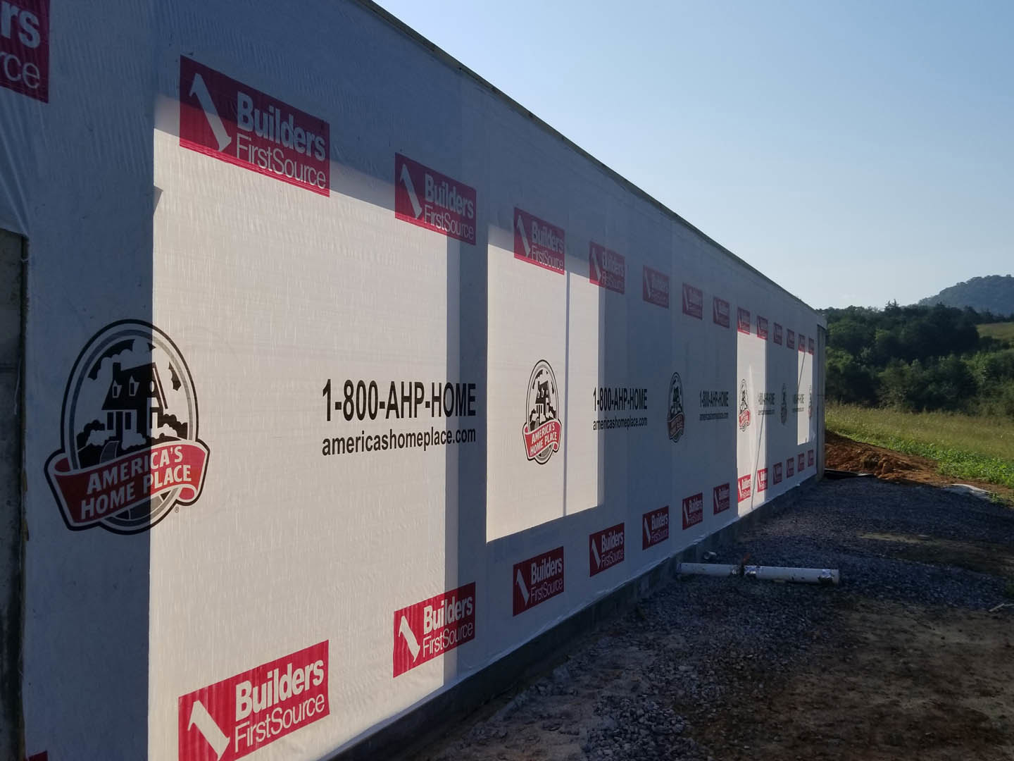 White exterior wall displaying red and white logos, surrounded by trees and sky in the background