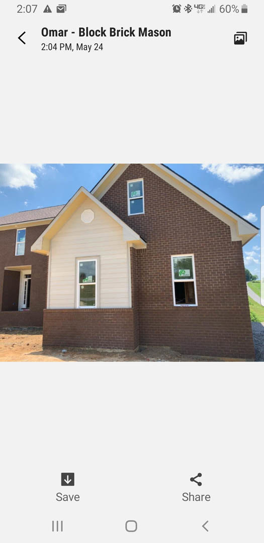 Red brick exterior with white and brown roof, single window displaying a sign, partly cloudy sky above